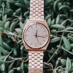 round gold-colored Nixon analog watch with link bracelet